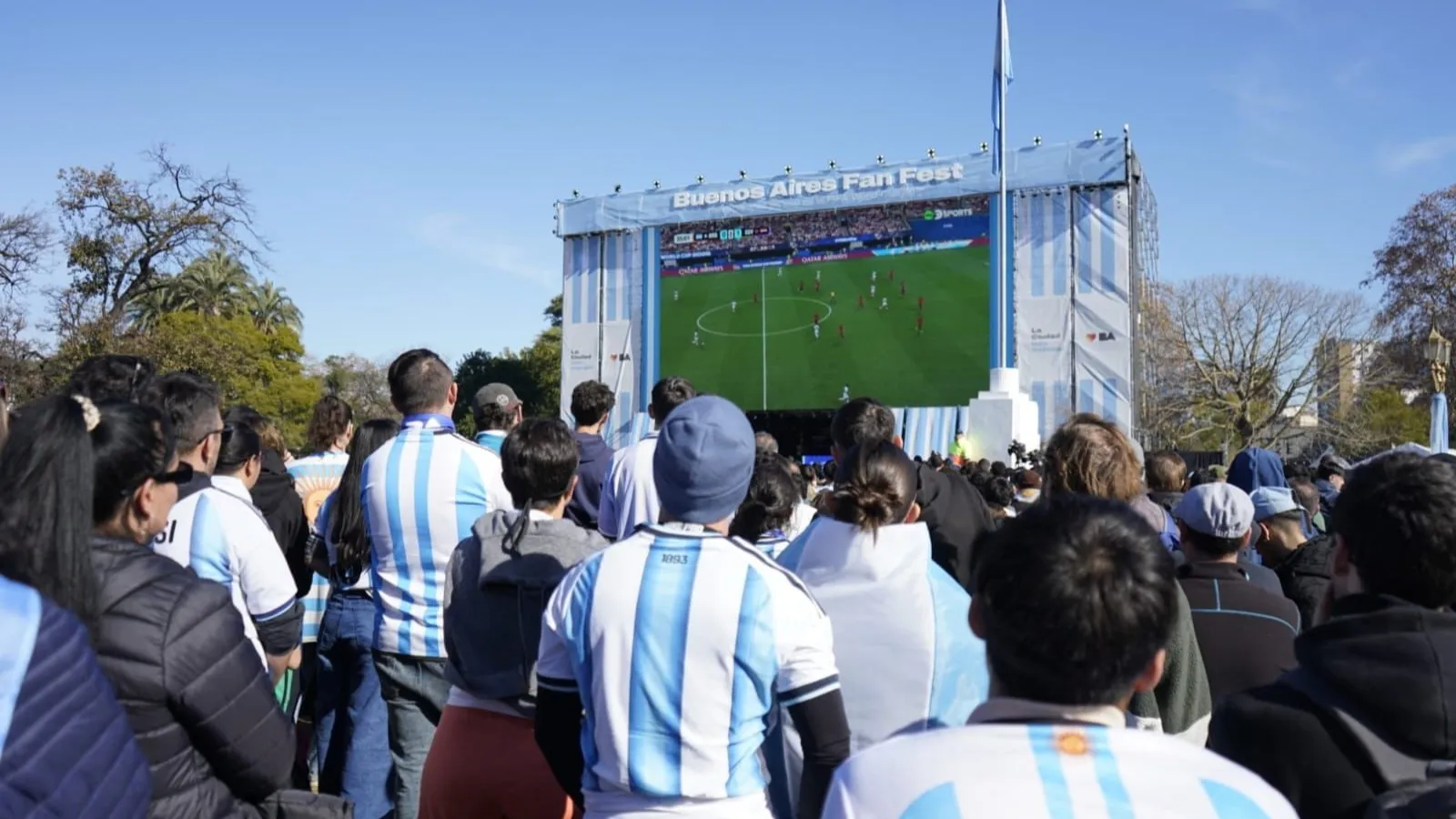 A crowd in Argentina shirts watches a match on the giant screen at the Buenos Aires Fan Fest